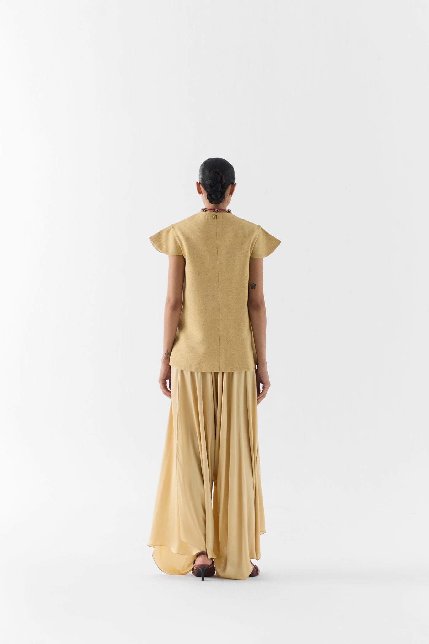 Close-up of gold garden rose print and fabric texture on the vest and dhoti pants